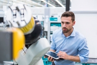 man using digital tablet standing at machine